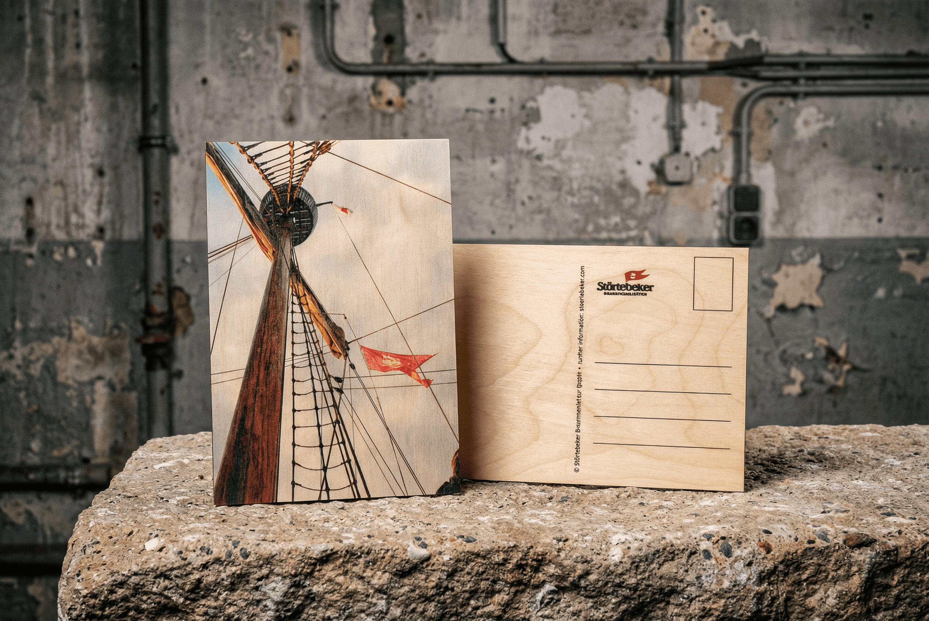 Wooden postcards on concrete, one shows ship mast and sails
