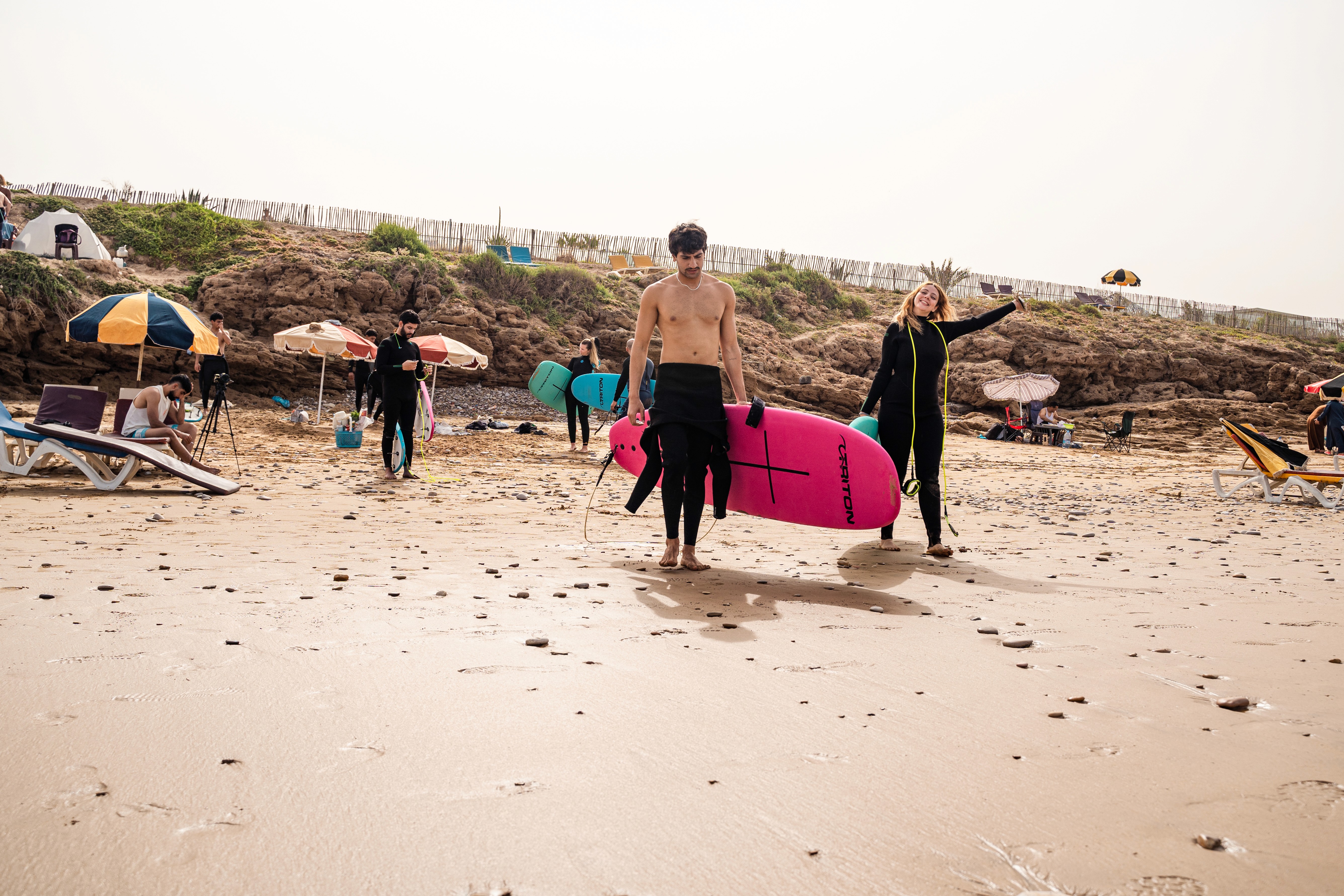 a group of people carrying surfboards on top of a beach
