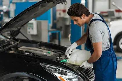 Young man adding oil to the car