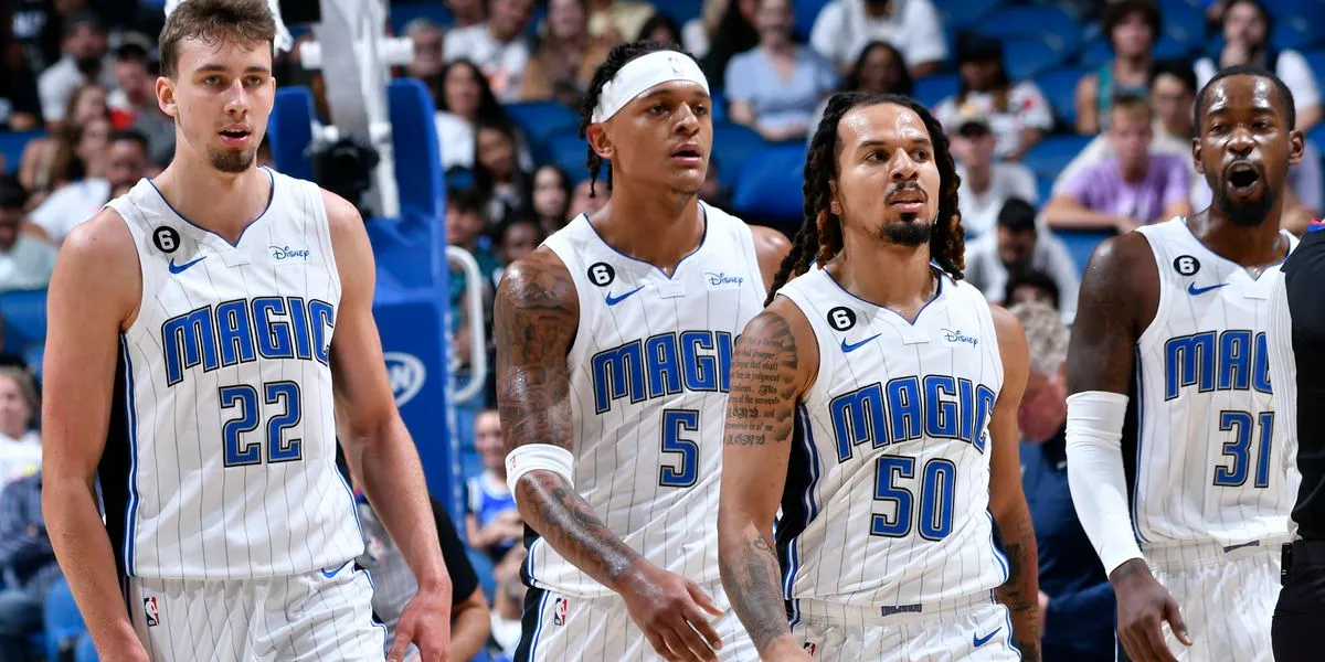 Group of Orlando Magic players in white uniforms walking together on the court during a home game.