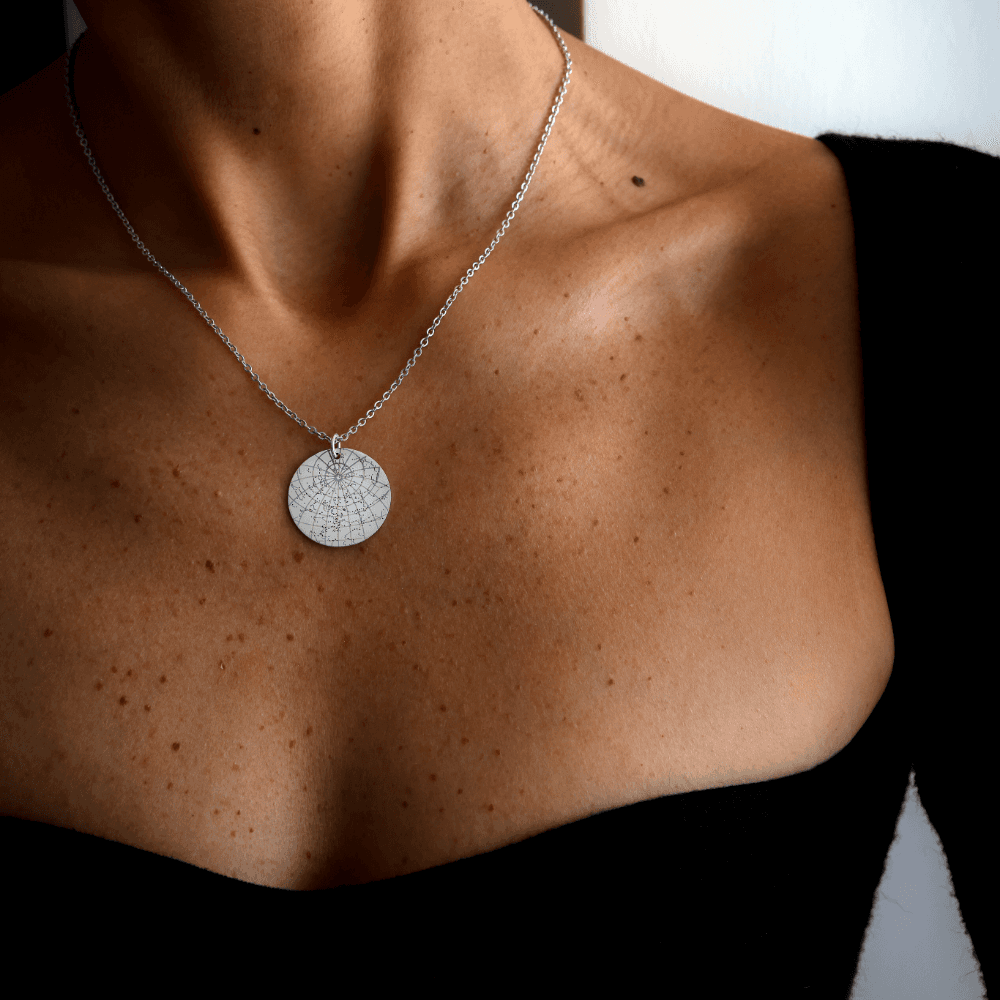 A woman's chest wearing a Night Sky Star Map silver pendant.