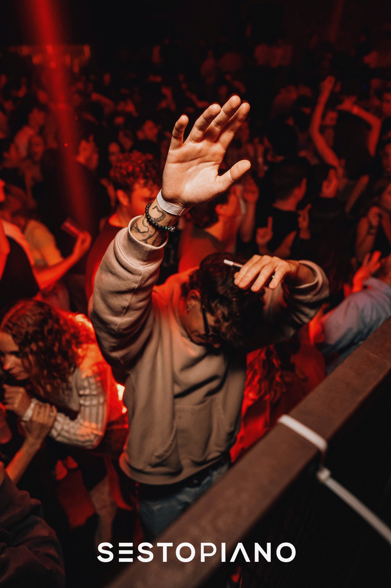 person rising hand enjoying music in a club with red backgroung