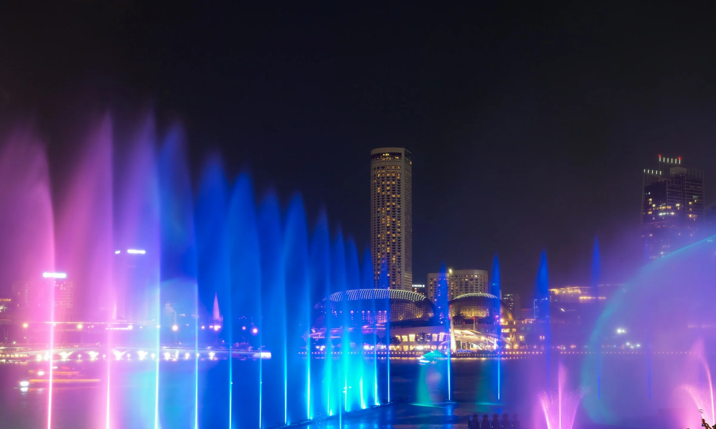 The fountains of Spectra at the Event Plaza, lit blue and violet