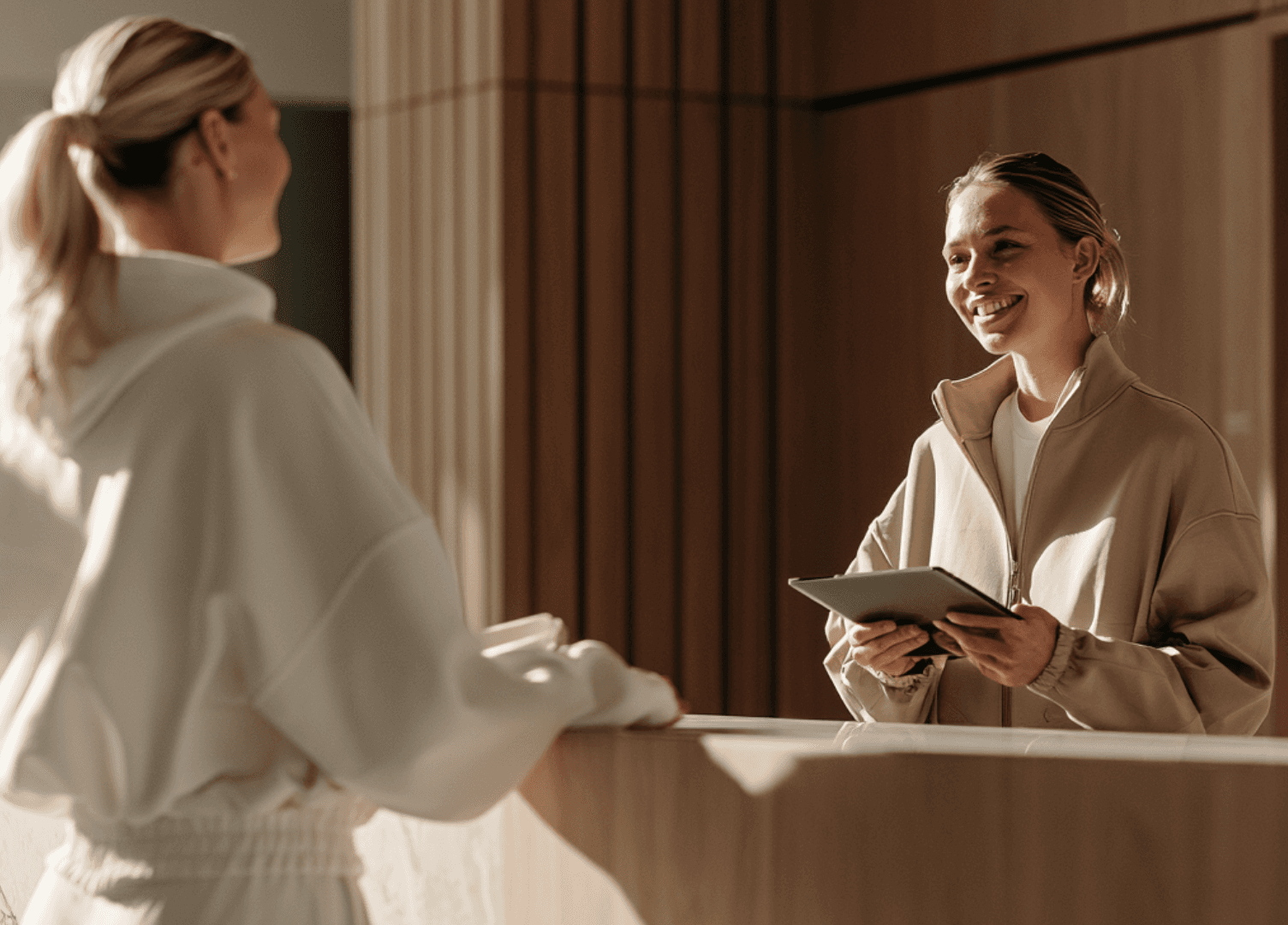 Front desk staff member welcoming a new client and confirming their next appointment on a tablet