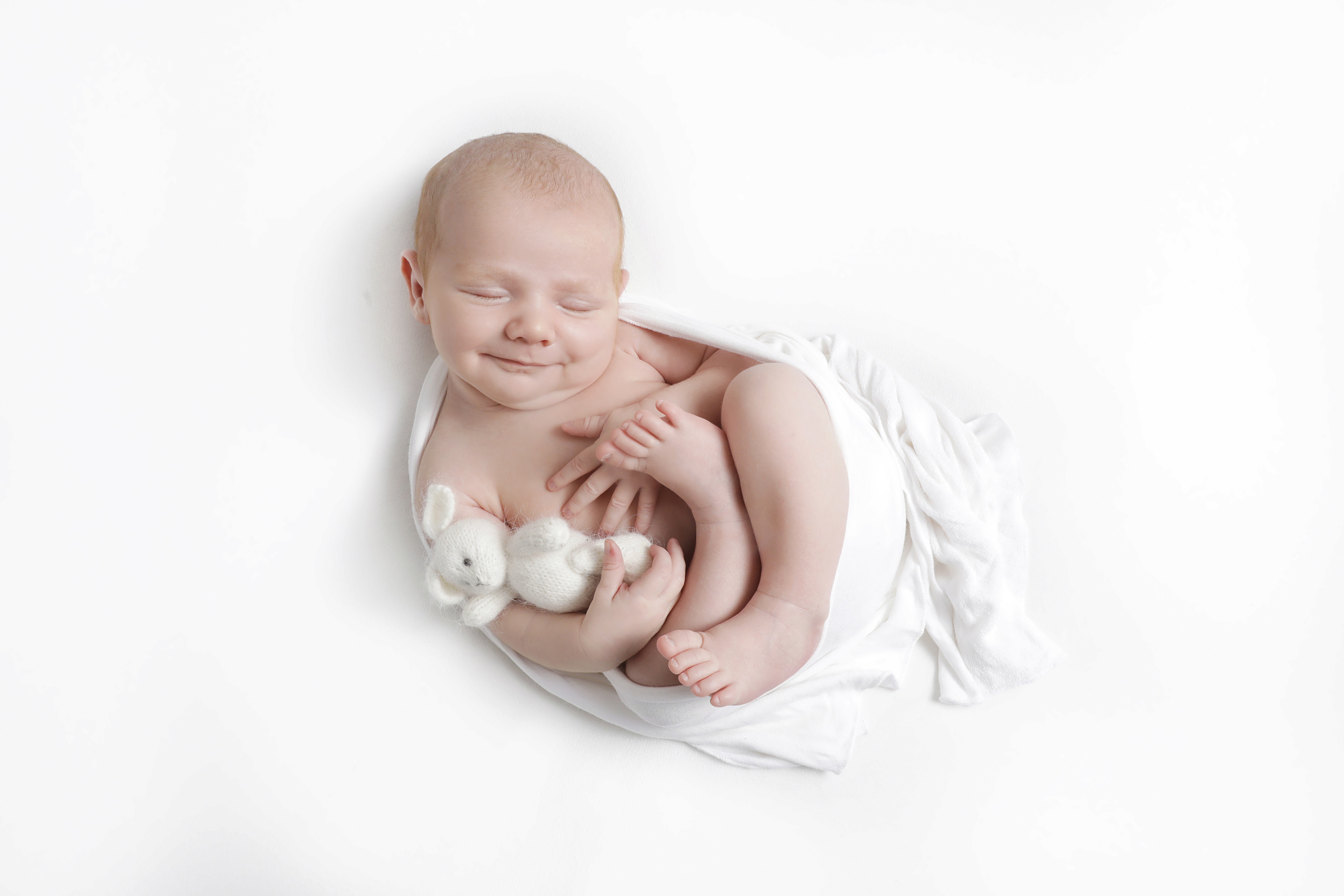 Sleeping baby smiling for a newborn hospital photo.