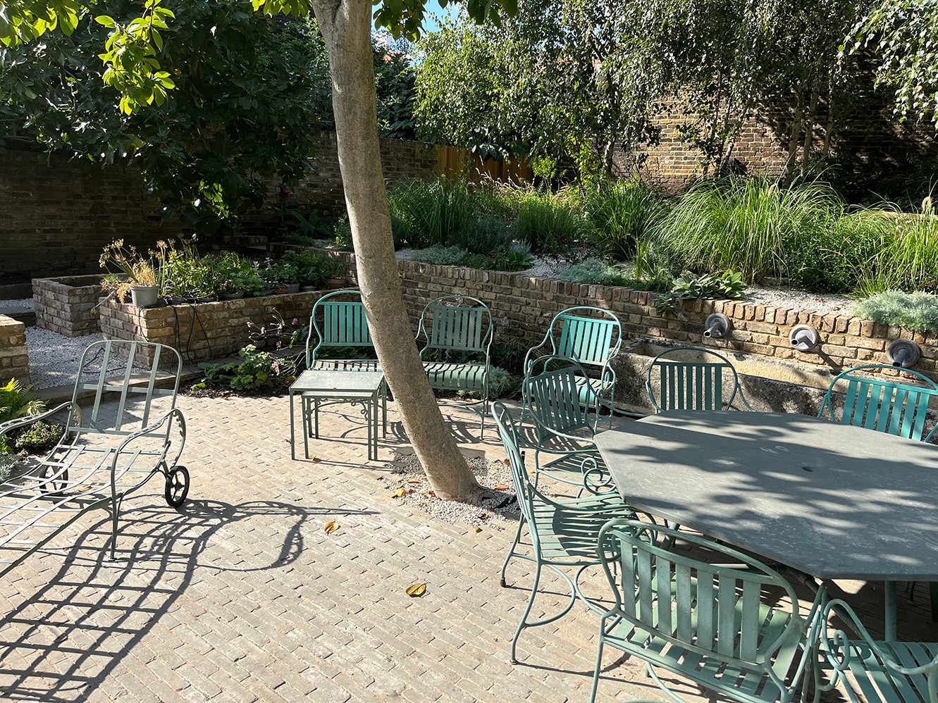 A tranquil outdoor space featuring a pool, lush greenery, and comfortable lounge chairs under sunlight.