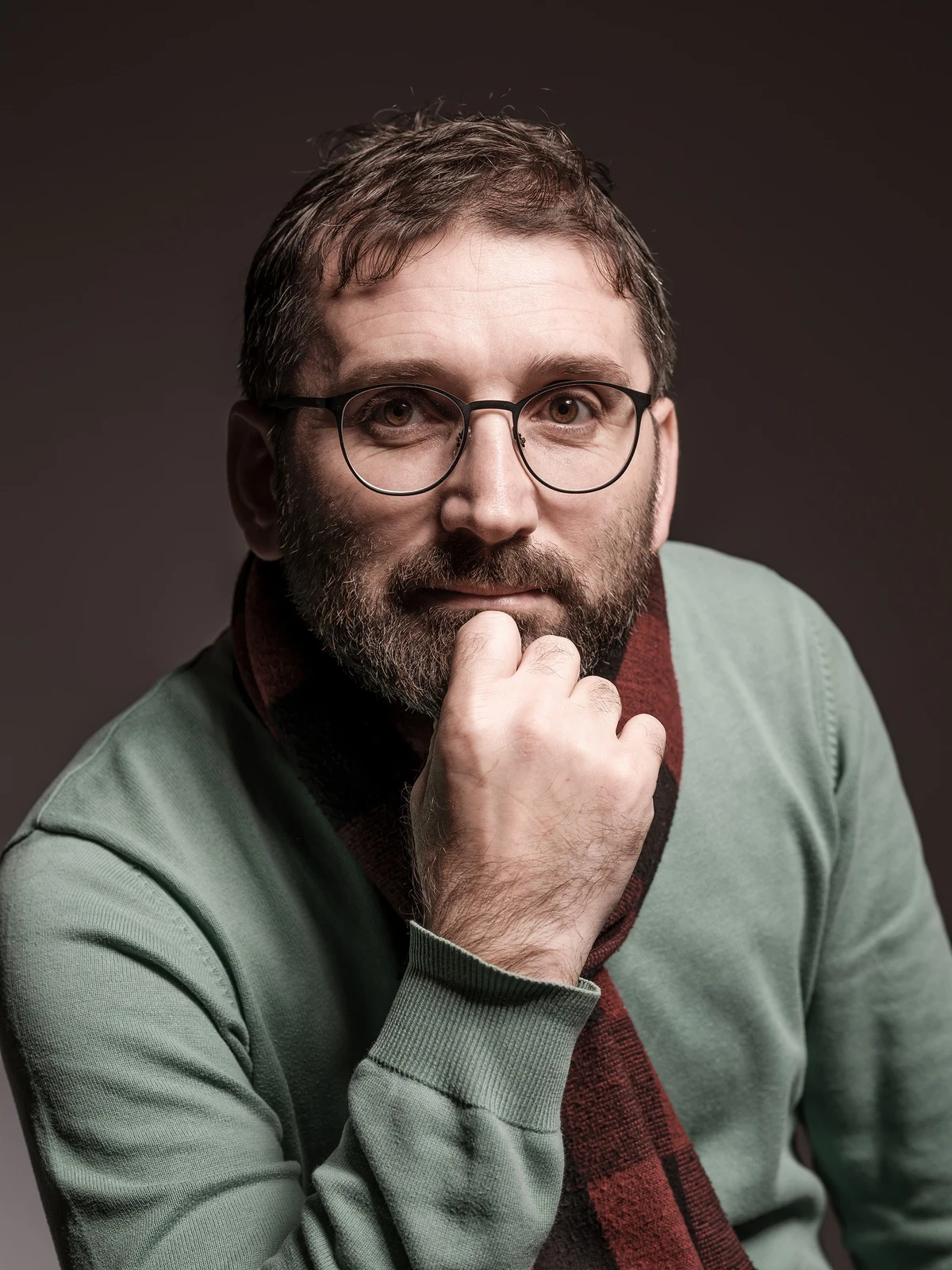 Close-up portrait of a freckled woman with soft pink hair and star earring, natural light, white tank top.