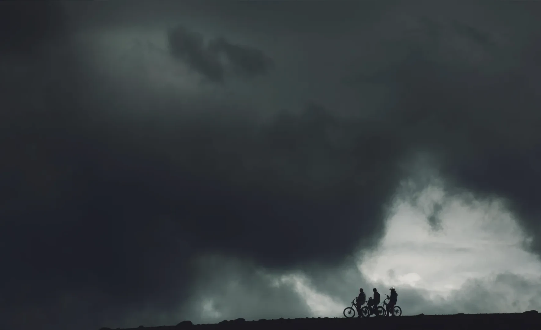 Big clouds and three bike riders silhouette