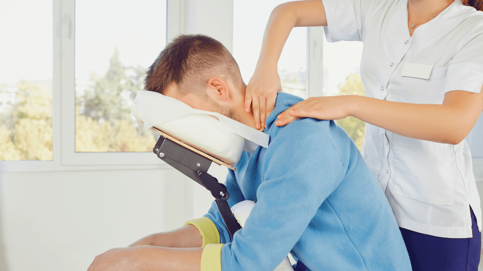 A winding road cuts through rocky terrain, surrounded by patches of green grass and illuminated by sunlight.