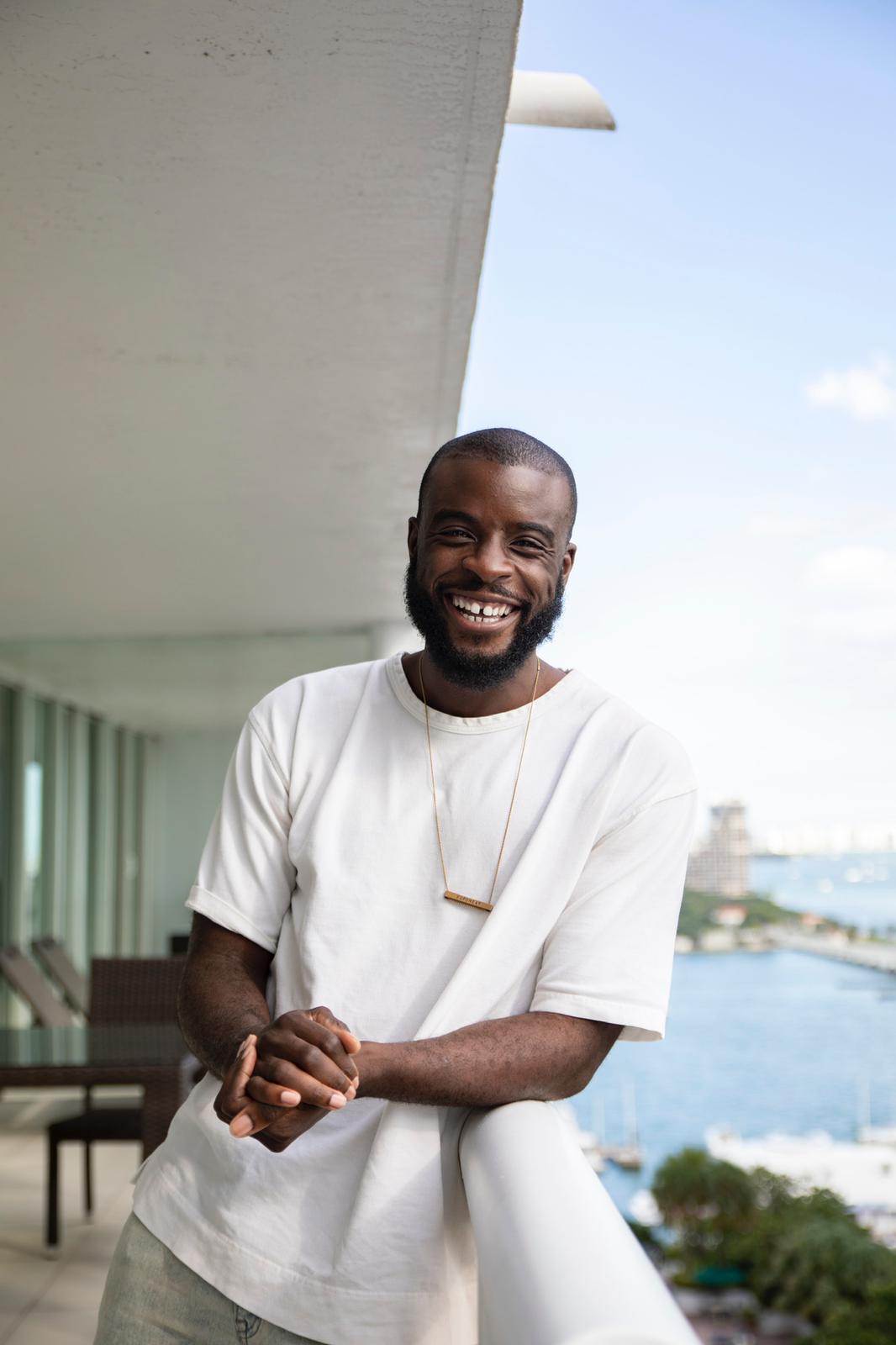 Two women sitting together in a cozy, well-lit workspace, smiling and collaborating over a laptop, with a coffee cup and a bowl on the table.