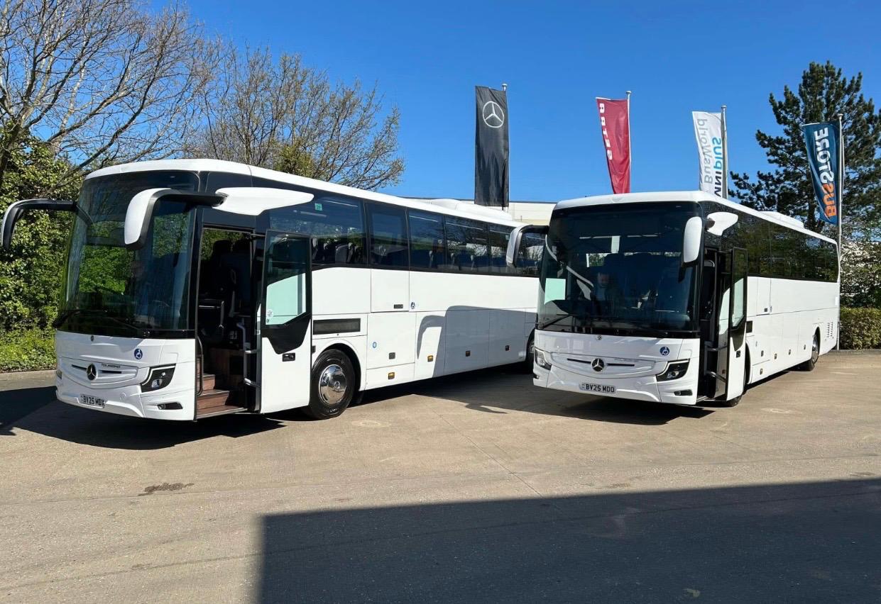 Modern luxury coach driving on a scenic highway at dusk, symbolizing premium and reliable travel services for business and private clients