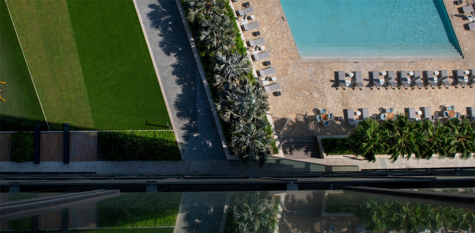 مشهد هادئ يضم مسبحًا محاطًا بمسطحات خضراء، يعكس أجواء الرفاهية في مشروع ون زعبيل السكني.