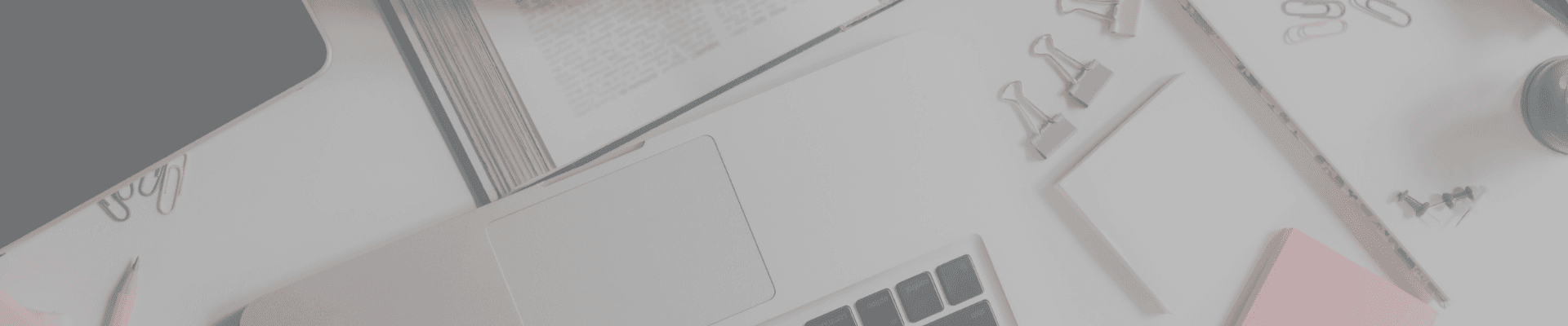 Flat lay of college study essentials including laptop, open book, paper clips, and notepad – part of a college packing list for academic success.