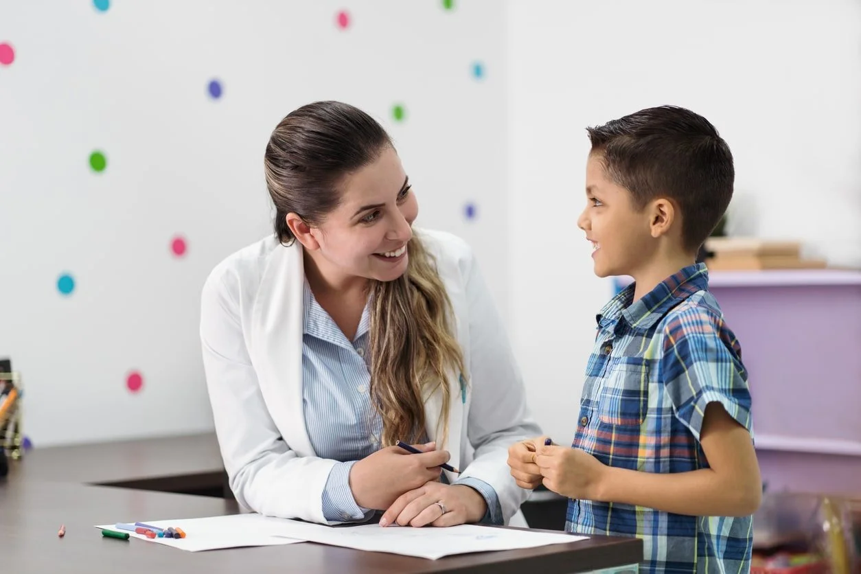 Child therapist guiding young child through play-based counseling session in a therapy room