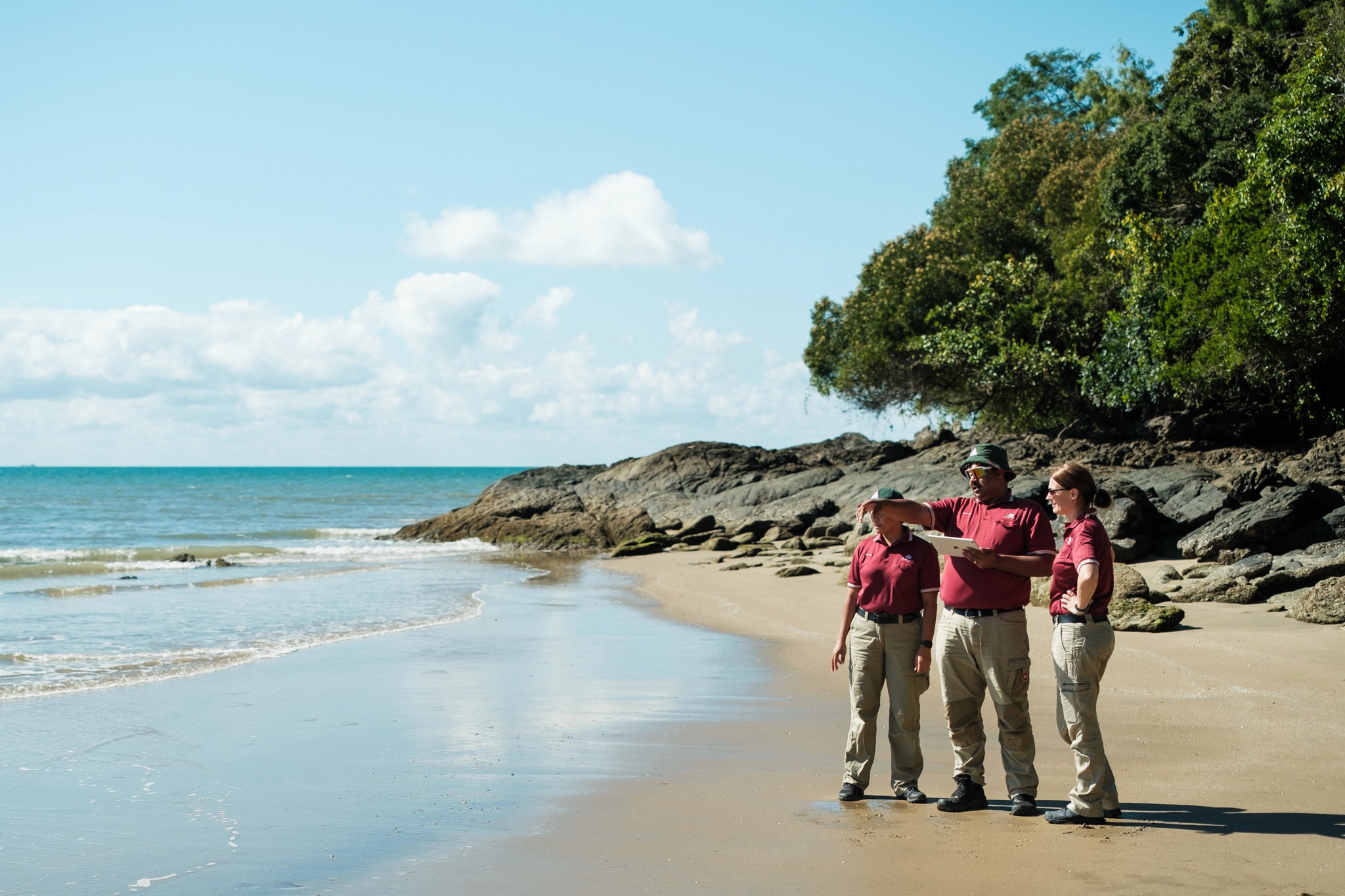 Three people stand on a beach