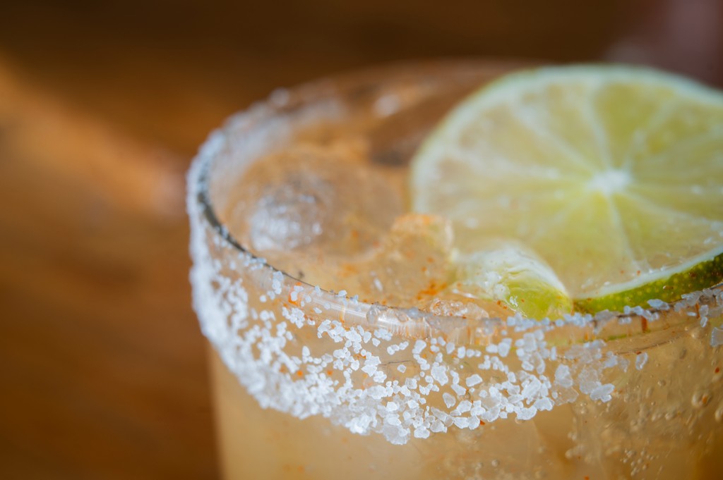 a glass of cocktail with a slime orange fruit