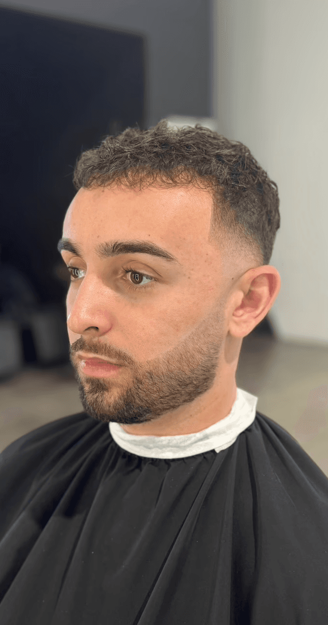 Sharp beard grooming with a mid fade and textured top, delivering a polished and professional look for modern men at The Rich Barber in West Hollywood.