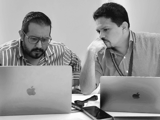 Juan Carlos y Alex observan y hablan mirando la pantalla de un laptop