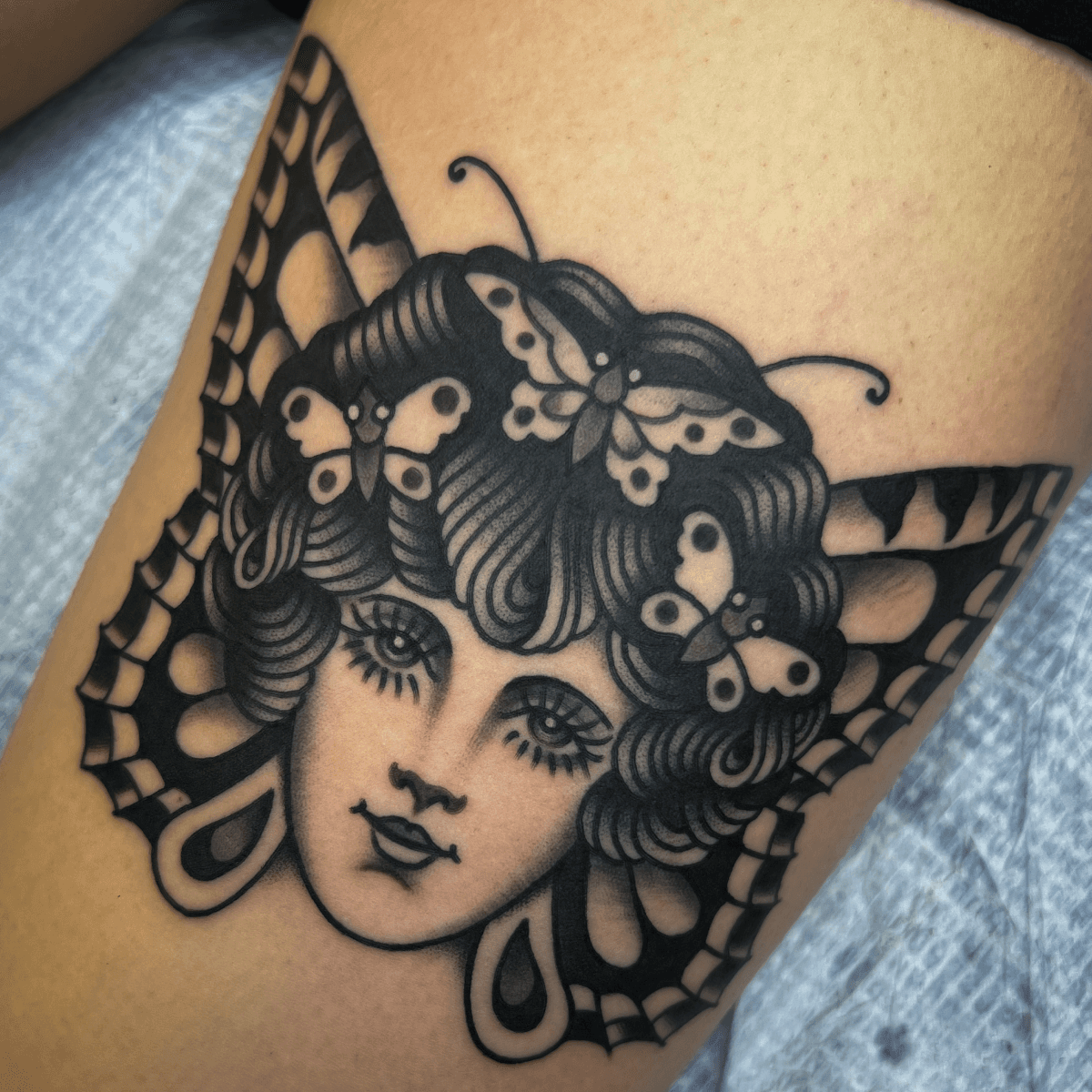 black and gray tattoo of a girl head with butterfly wings