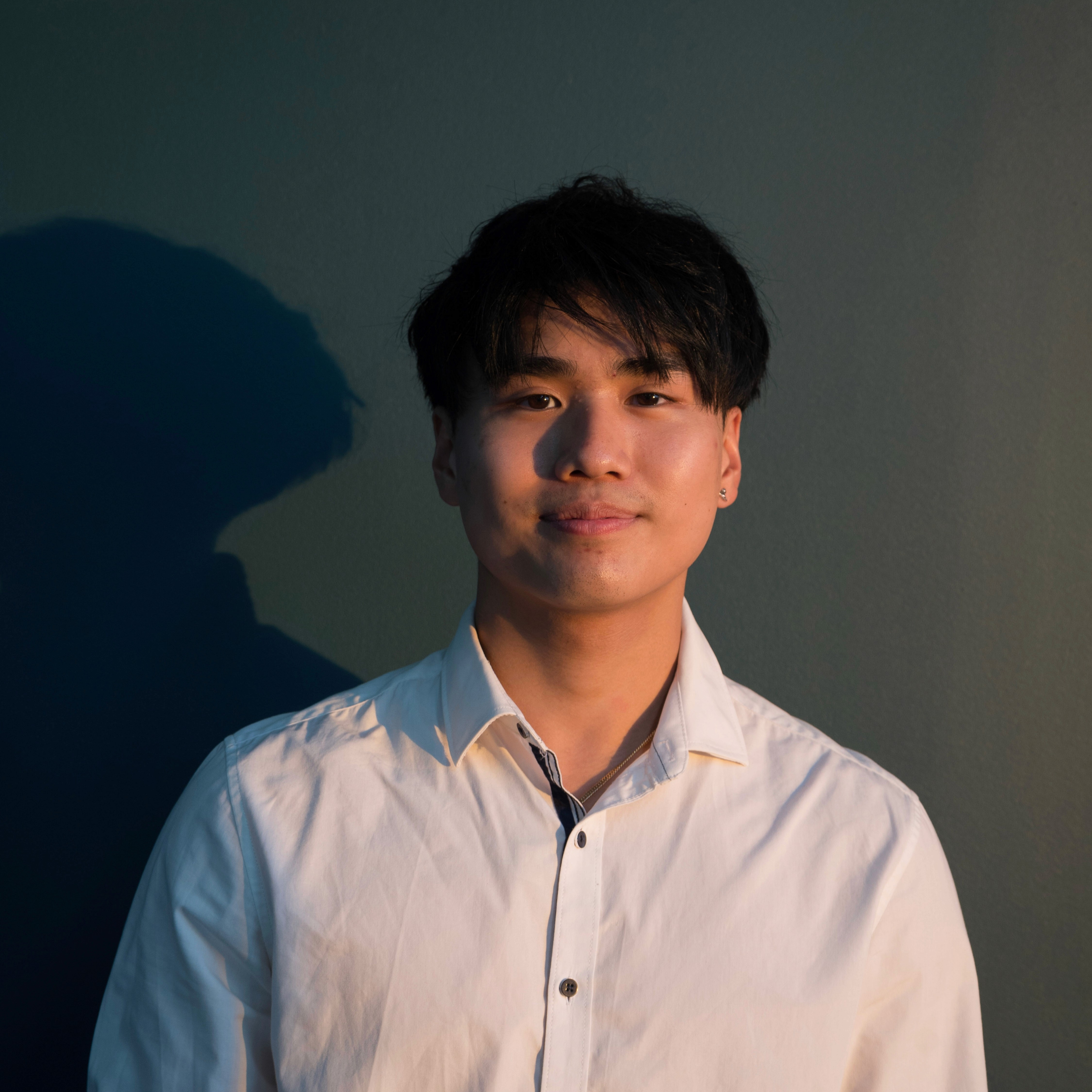 Portrait of Doni Pham, Managing Director at Conxept Agency, wearing a white collared shirt against a dark background, facing forward with a calm expression.