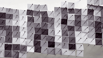 A grid of square patches in varying shades of gray and white is arranged on a light gray surface. The patches are closely packed and overlap in places, with some areas appearing darker due to shadowing or thicker application. The patches are oriented in different directions, creating a dynamic and textured appearance.