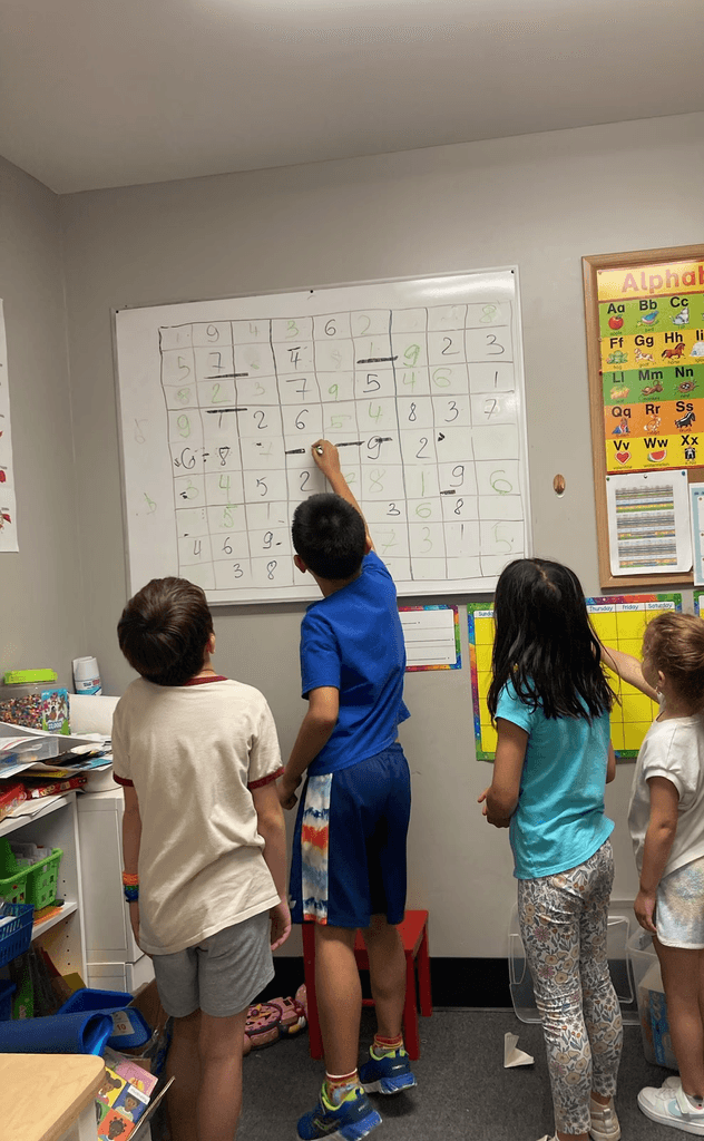 Four kids at a SportPlus math class solving a sudoku math challenge on a whiteboard