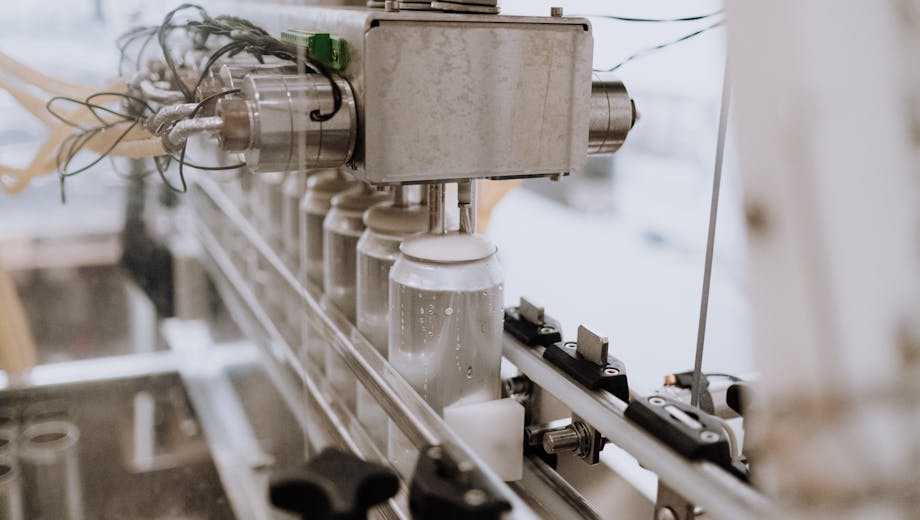 Close-up of an automated can filling machine in a beverage production line.