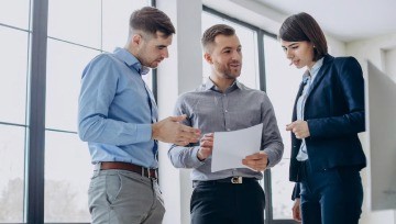 Person working at a desk while reviewing a tax form displayed on a computer screen.
