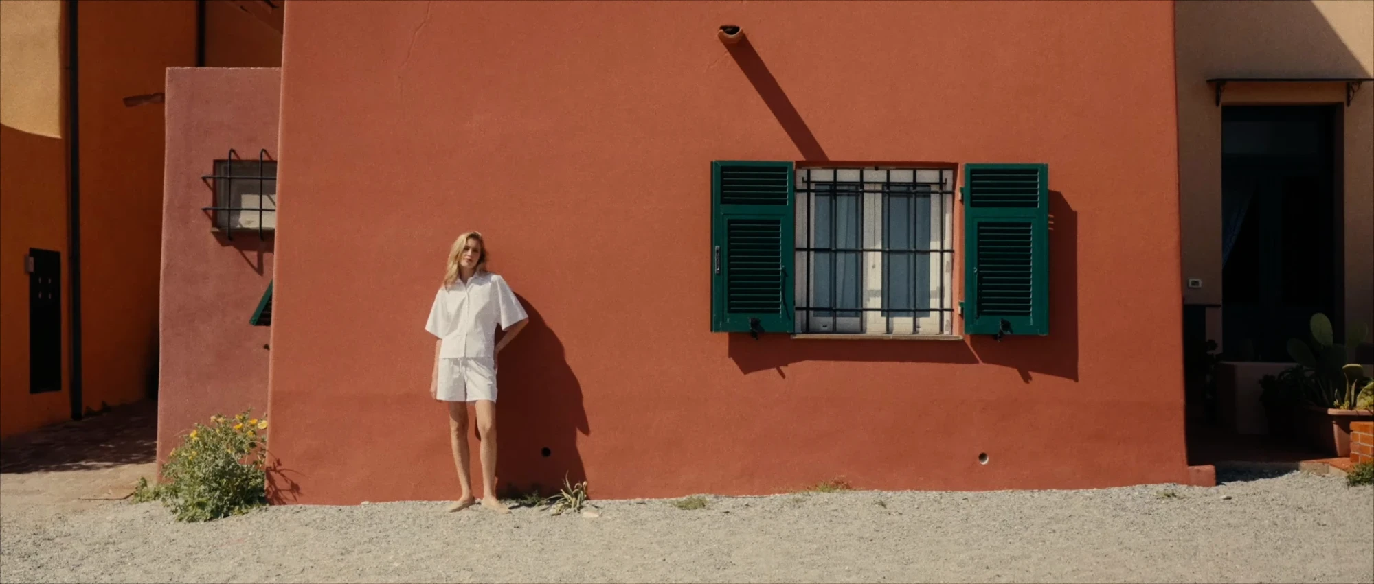 Model beside a red building with green shutters