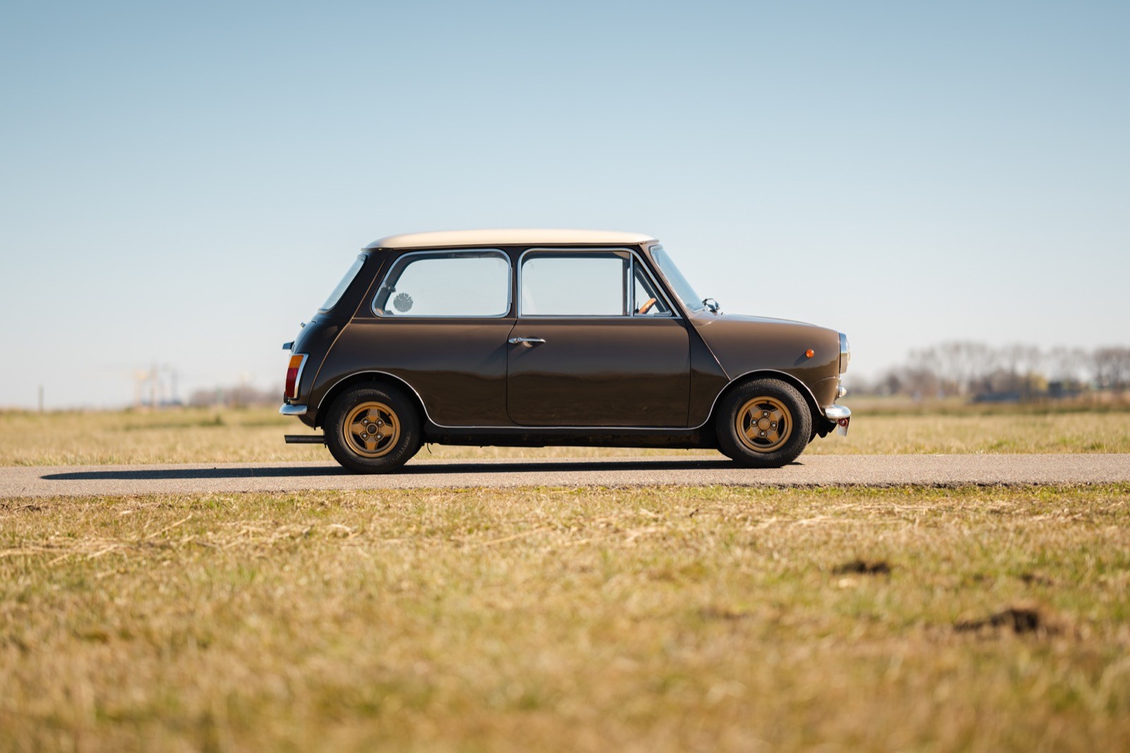 A profile view of a compact black car parked on a barren landscape under a clear blue sky.