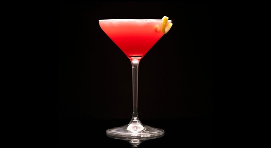 A closeup of a Pomegranate Martini drink against a dark background.