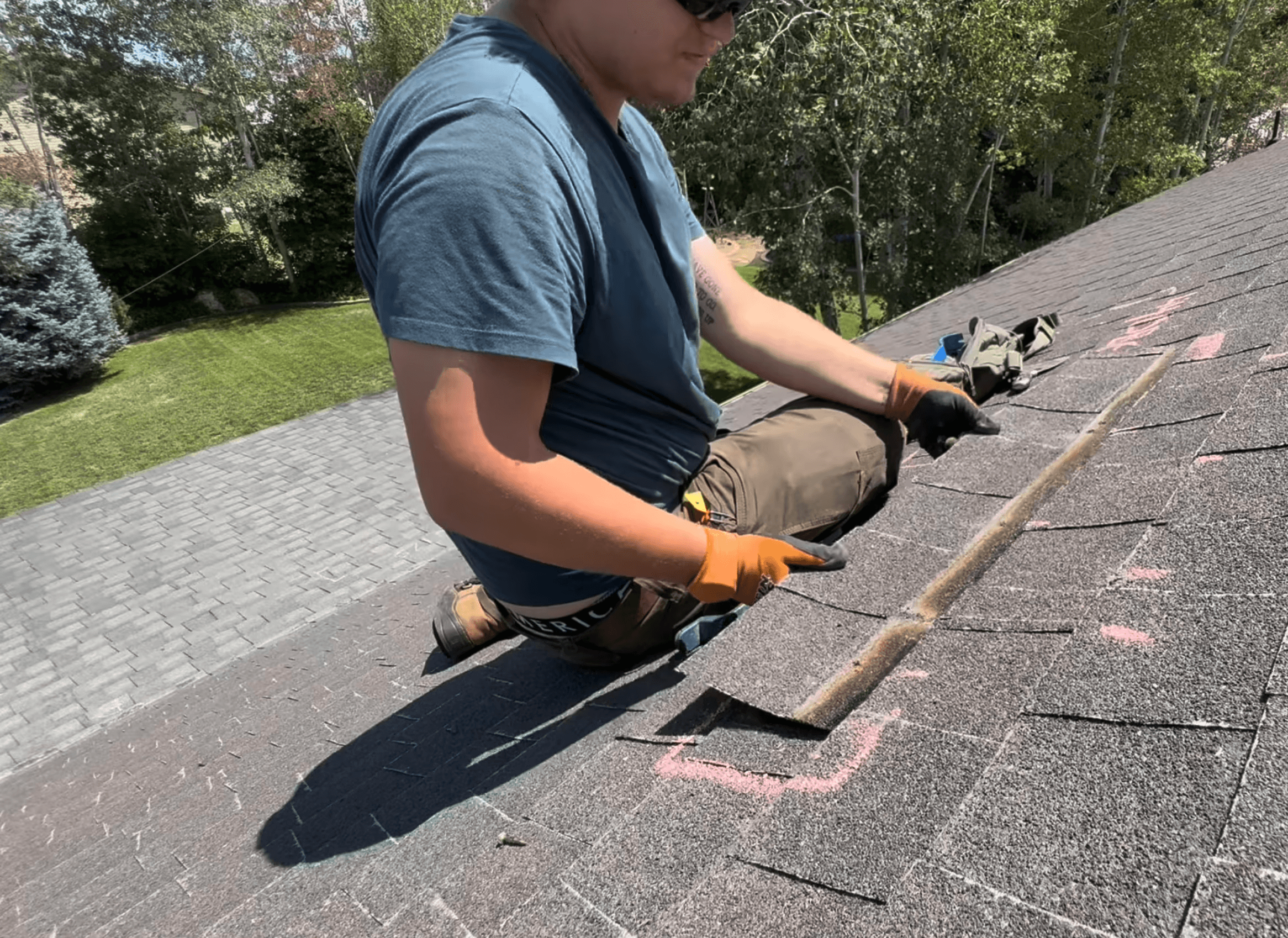 Roofer marking storm damage on a shingle roof with chalk during an inspection