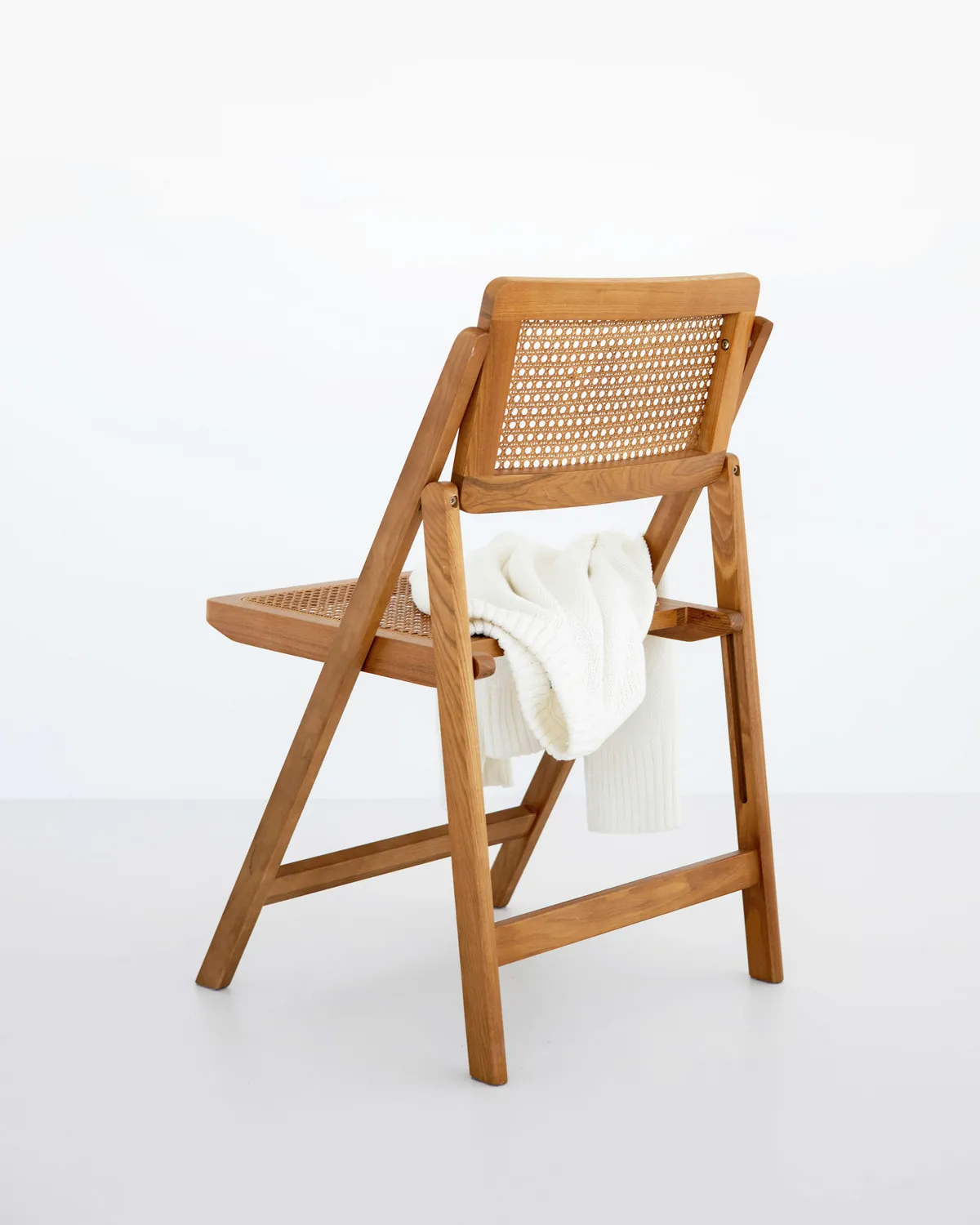 Folding cane chair in cherry, woven cane, in a room