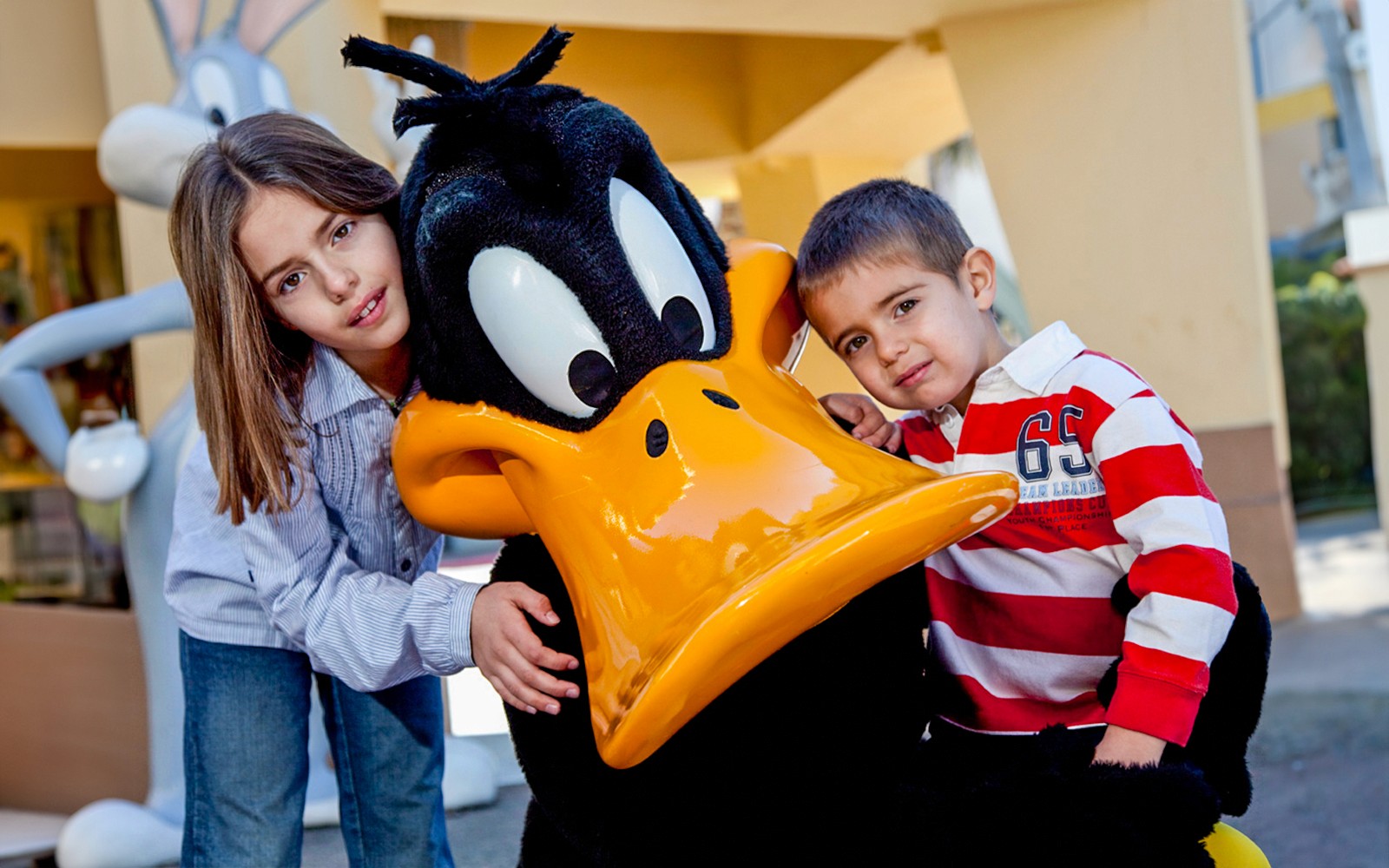 Crianças a posar com uma personagem de animação num parque temático.