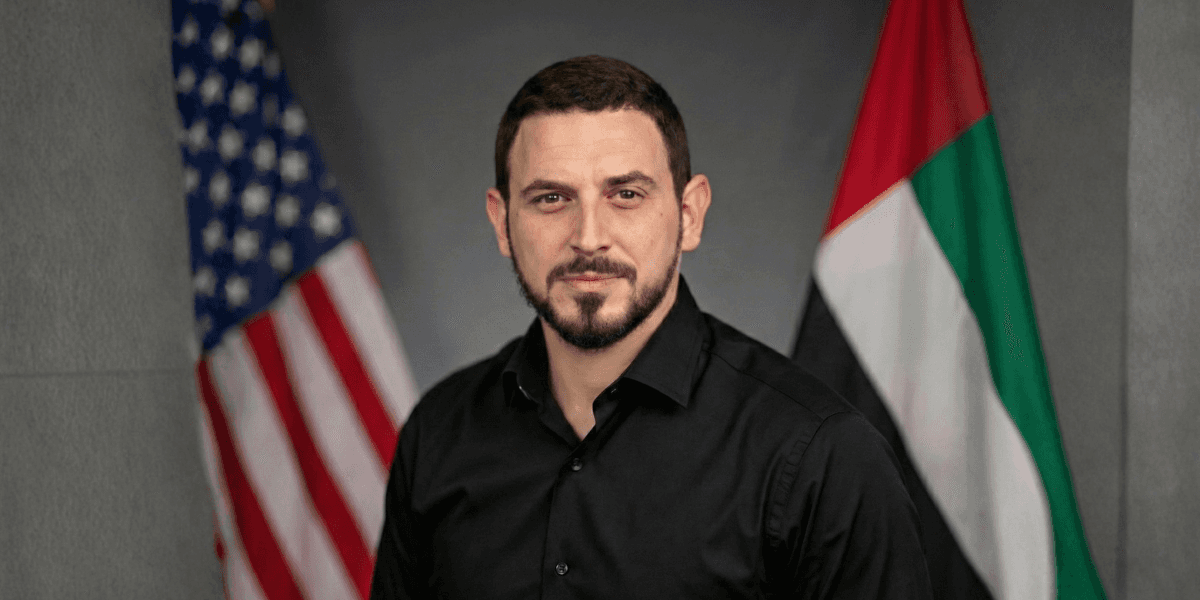 Omri Raiter, CEO of RAKIA, standing confidently with the U.S. and UAE flags in the background.