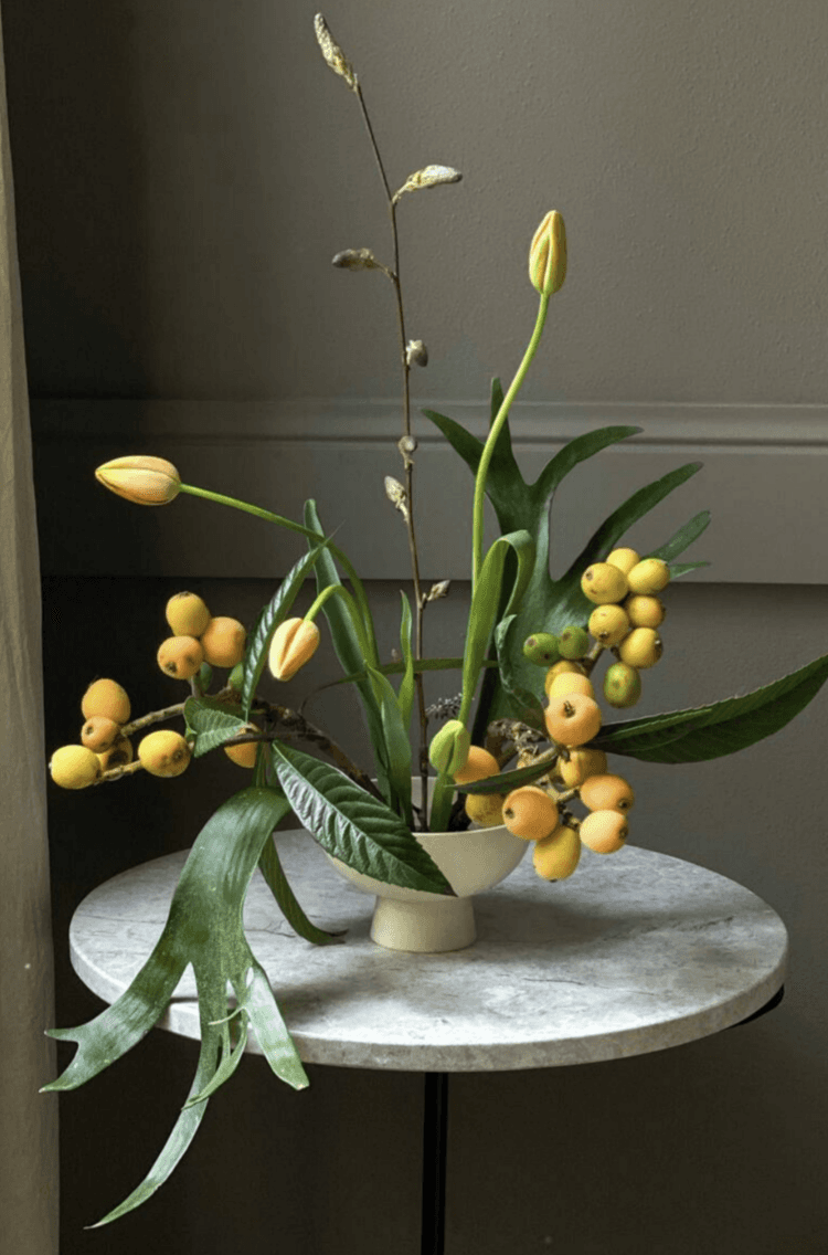 Arreglo floral contemporáneo por Irina Khatsernova con tulipanes y frutos — diseño escultórico en estilo naturalista.