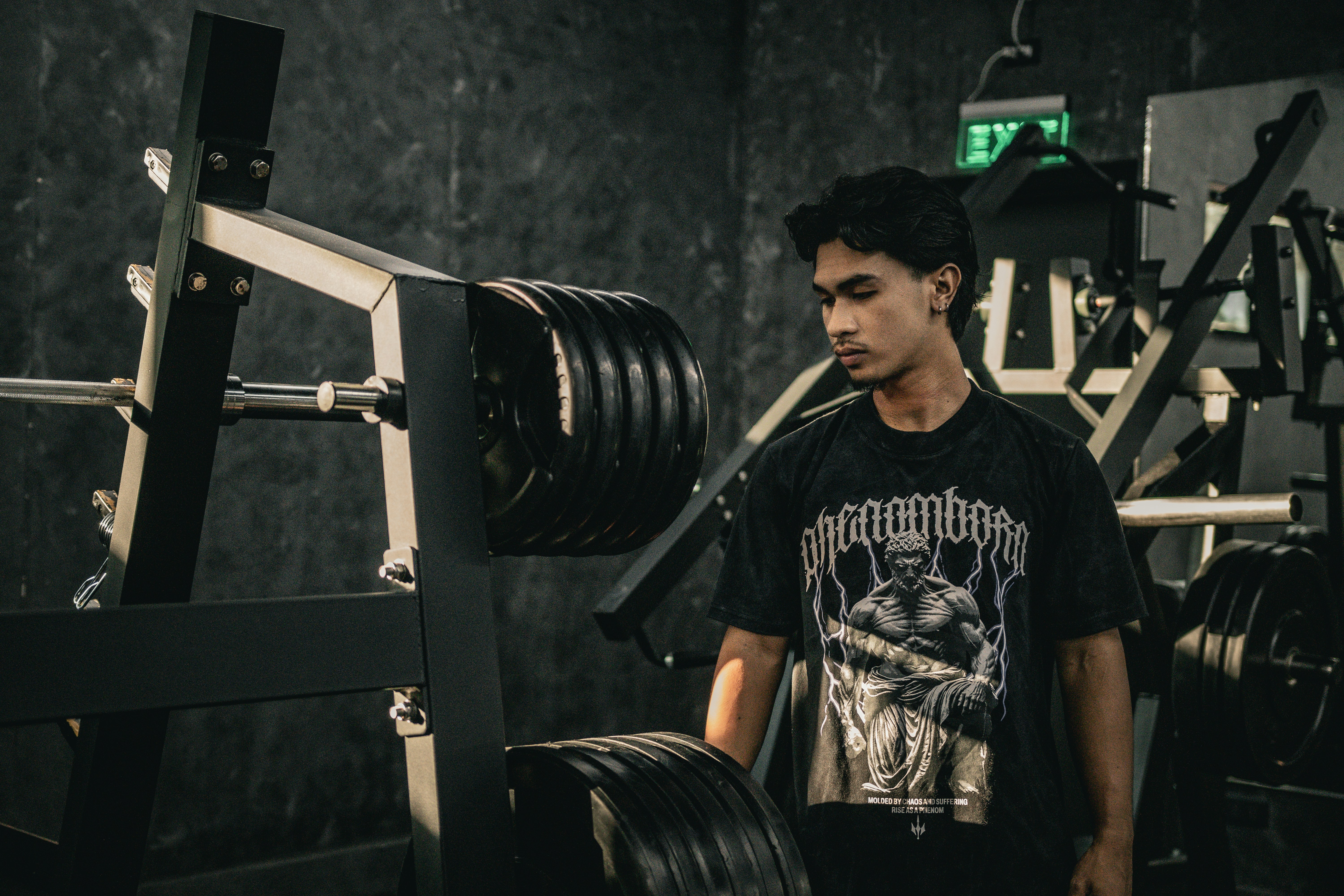 A man standing next to a barbell in a gym
