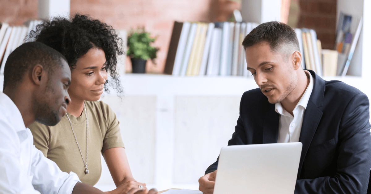 business professional sitting with african american couple looking at a computer