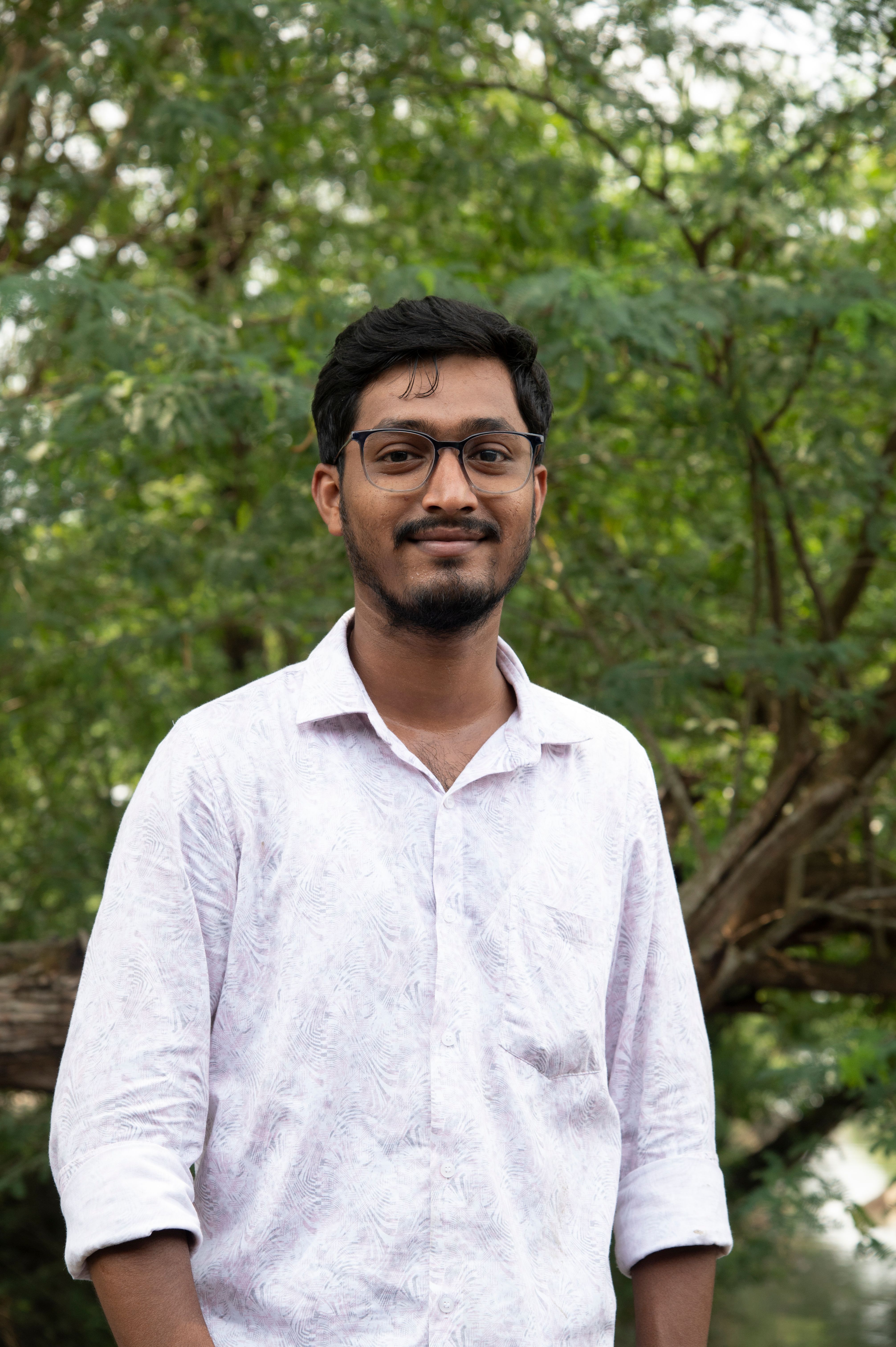 A person standing outdoors with trees around.