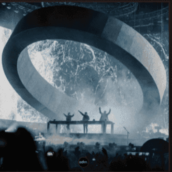 A crowd in front of a lit stage at a live show