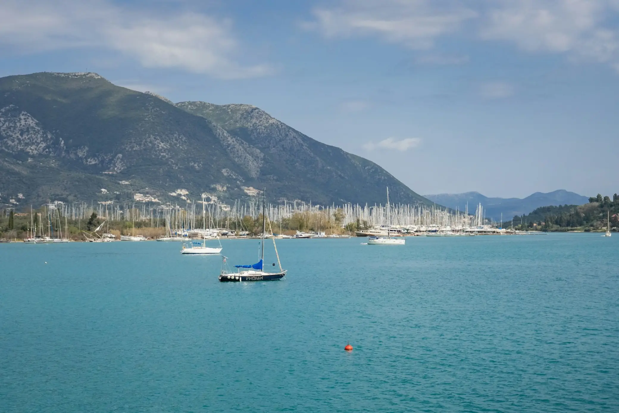 Voiliers dans une baie lumineuse de la mer Ionienne, montagnes en arrière-plan