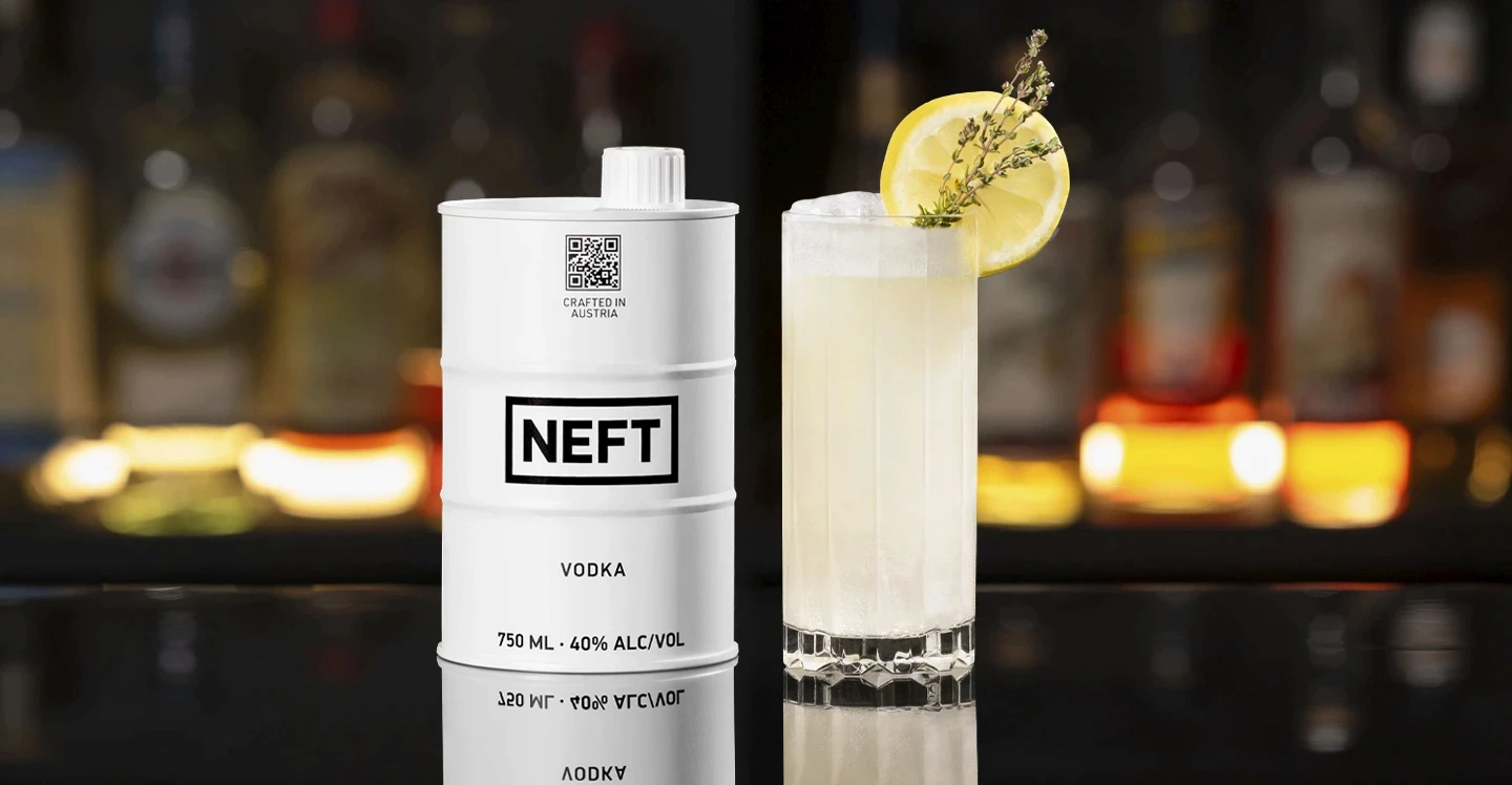 A NEFT Vodka Barrel and a glass of Summer Thyme Lemonade on a bar counter.