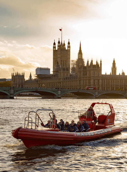 Thames Rockets Speedboat Experience: The sleek red Thames Rocket RIB speeds in front of the Tower of London with the setting sun in the back.