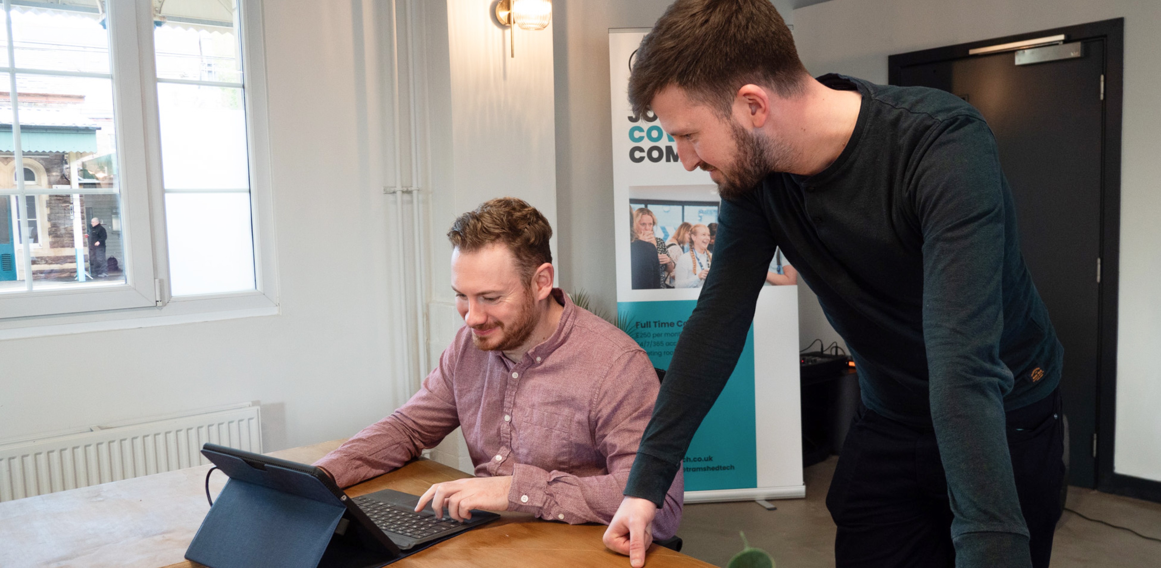 Two people working at a table with laptops.