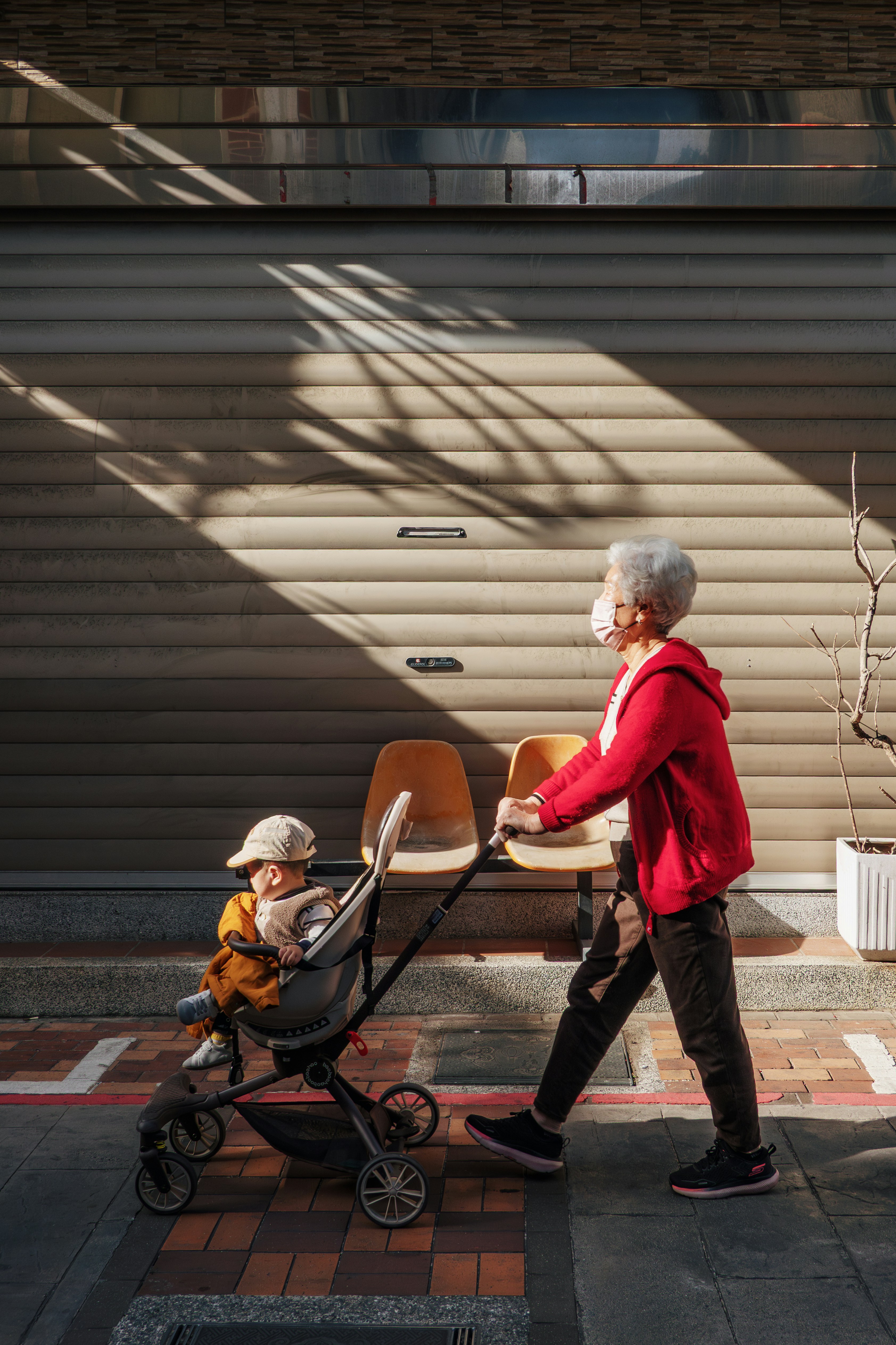 Elderly person with mask pushes child in stroller