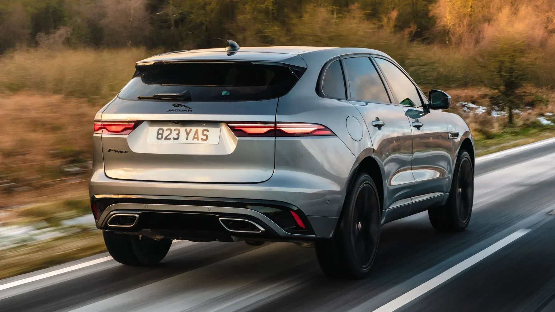 Rear view of a silver luxury SUV driving on a road