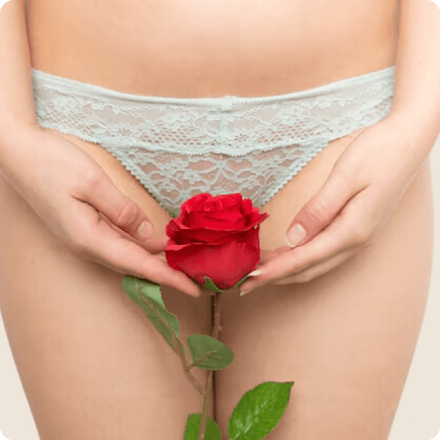 Close-up of a young woman gently holding a flower near her vaginal area, symbolizing femininity and self-care. The image conveys a sense of empowerment and confidence, emphasizing the theme of vaginal rejuvenation and personal well-being. The soft lighting and focus on the flower add a serene and delicate touch to the composition.