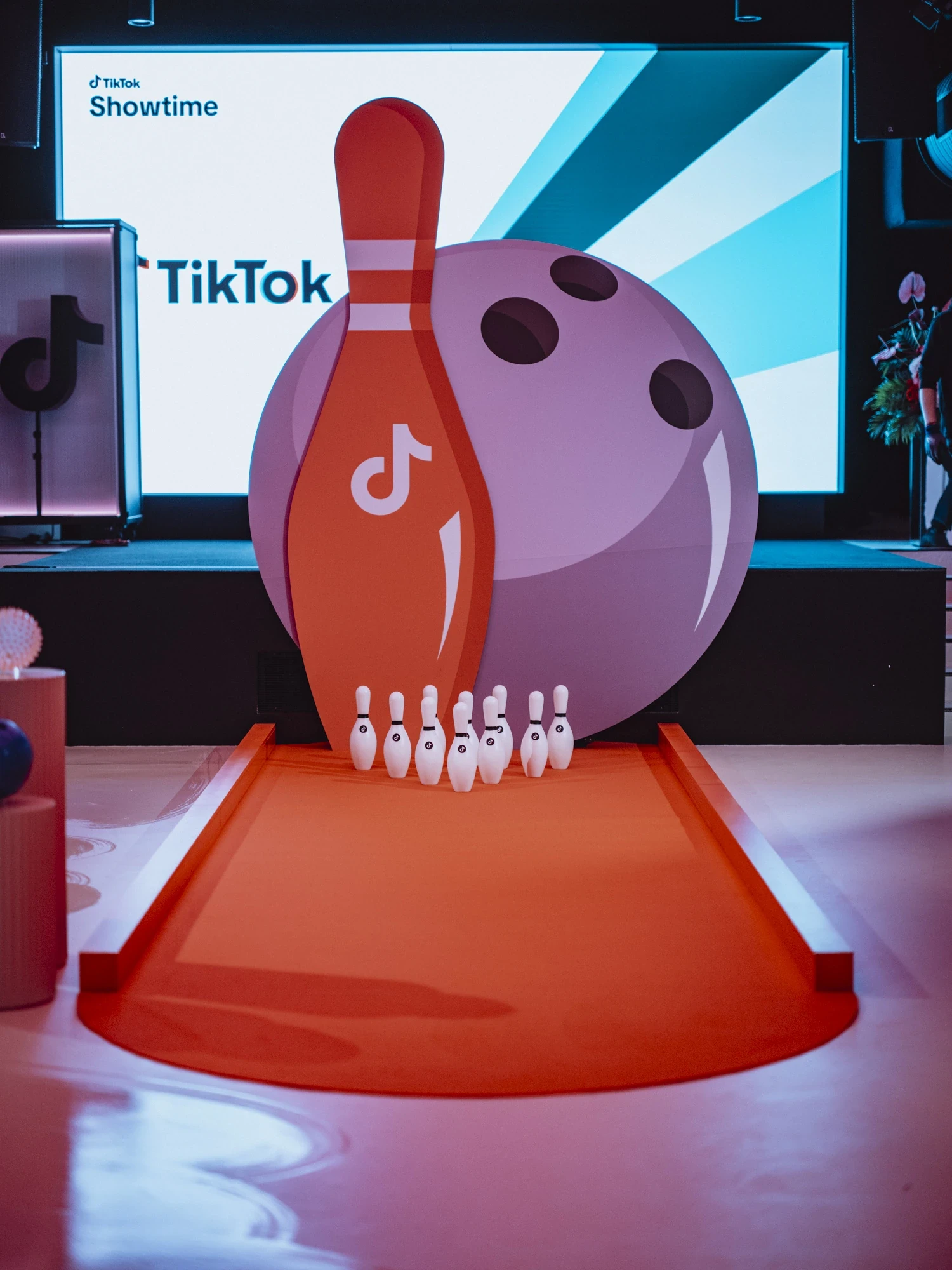 Oversized bowling installation with a pin and ball in TikTok branding in front of an LED screen, staged on a red carpet lane at the TikTok Showtime event.