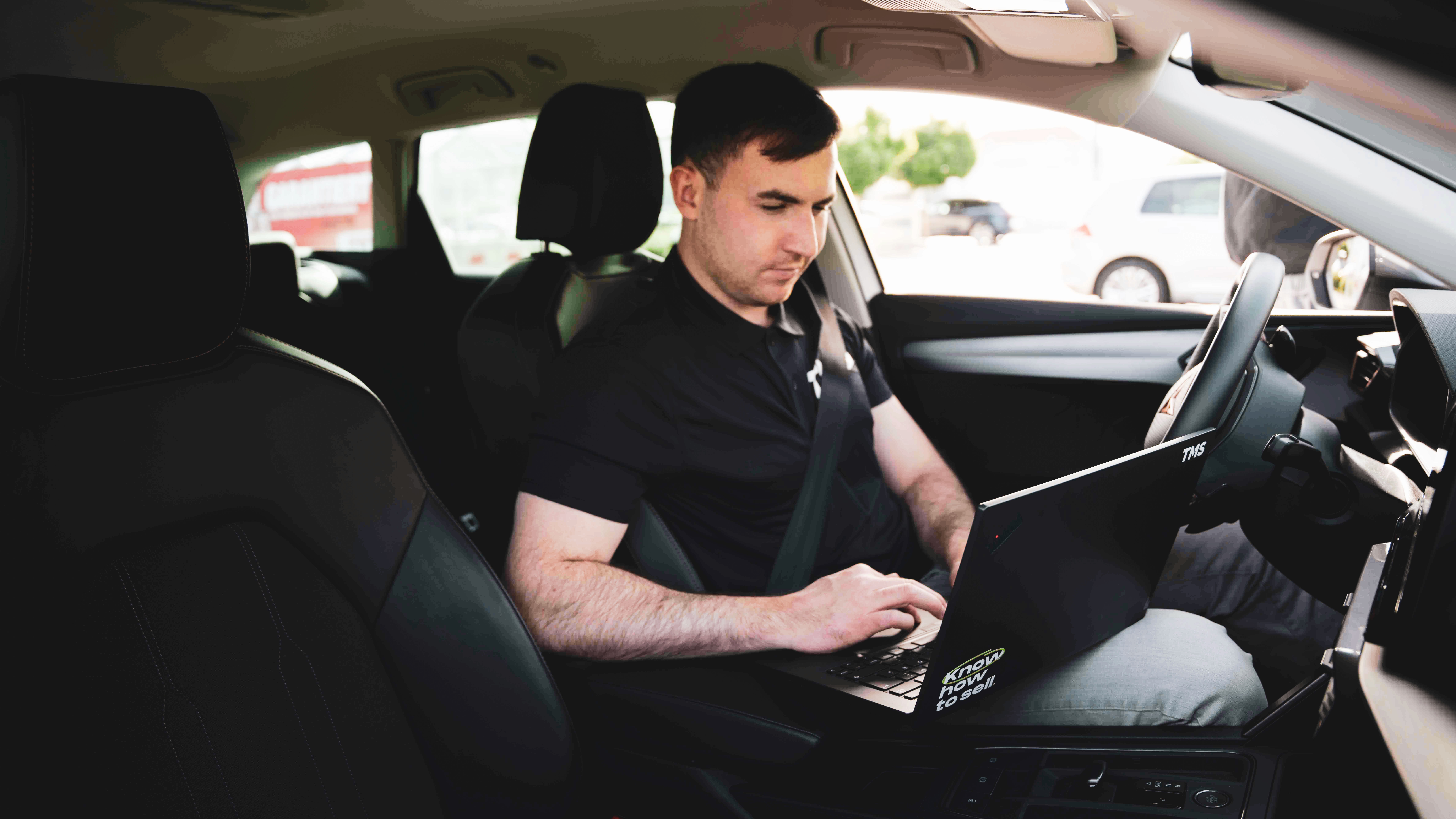 Mitarbeiter sitzt im Firmenfahrzeug und arbeitet mit einem Tablet. Steht für Flexibilität, mobiles Arbeiten und moderne Technik.