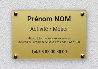 Plaque métallique dorée sur un mur texturé affichant un texte par défaut en français pour le nom, la profession et les coordonnées. Ton professionnel et formel.